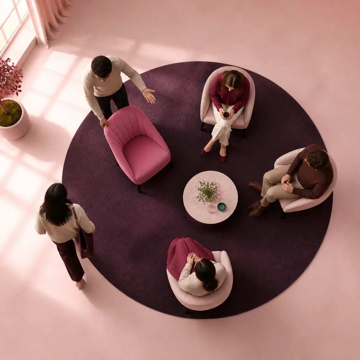 A person pulls an empty rose chair into a small social circle for someone approaching.